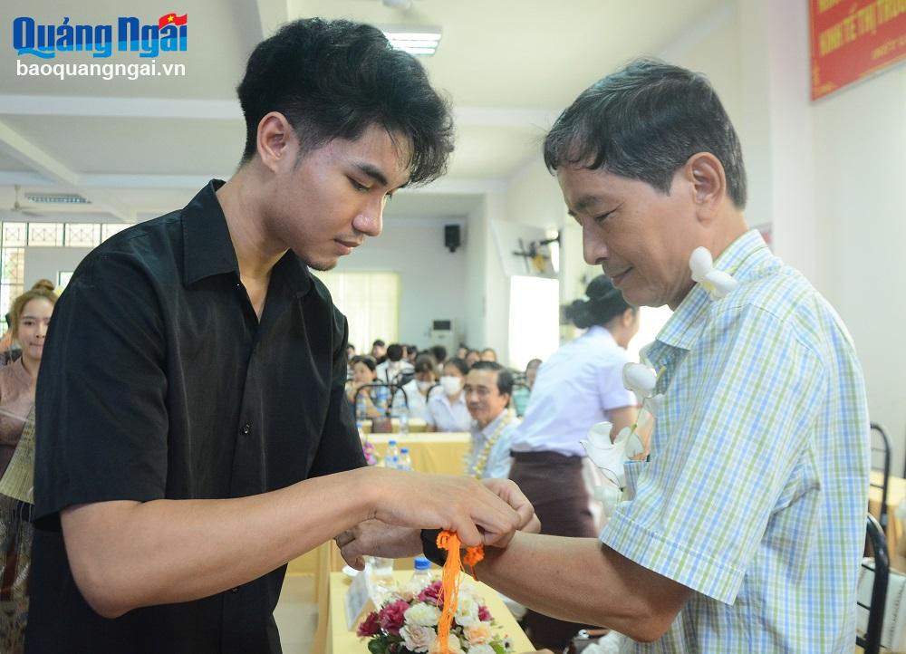 Các đại biểu và sinh viên Lào cùng nhau làm lễ buộc chỉ cổ tay.