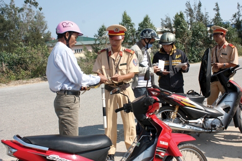 Cảnh sát giao thông kiểm tra giấy tờ xe, nhắc nhở người tham gia giao thông chấp hành các quy định về TTATGT.     