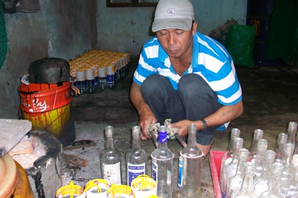 Anh Nam đang thực hiện công đoạn cắt vỏ chai thuỷ tinh để làm vỏ bên ngoài tại “xưởng” của mình