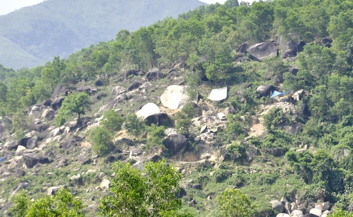 Những khối đá bị khai thác nham nhở nằm giữa sườn núi.