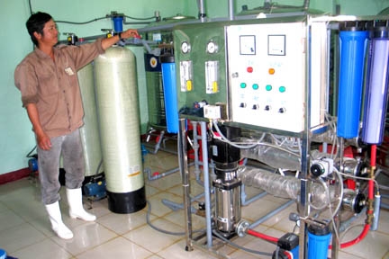 Công nhân đang vận hành dây chuyền sản xuất nước tinh khiết đóng chai của HTX DVCư điện Phổ Thạnh.