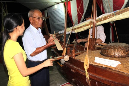 Ông Võ Hiển Đạt đang giới thiệu chiếc kinh thuyền cho sinh viên Trường đại học Phạm Văn Đồng.