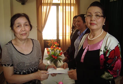 Bà Huỳnh Thị Tri (bên phải) trao tiền hỗ trợ cho chị Nhàn - tiểu thương bị thiệt hại lớn trong vụ cháy chợ Trung tâm TP Quảng Ngãi vào rạng sáng ngày 9/2.