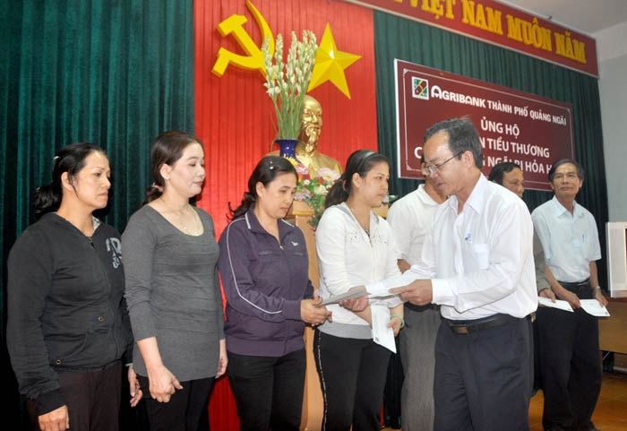 Đại diện Agribank Quảng Ngãi trao tiền hỗ trợ cho các tiểu thương.