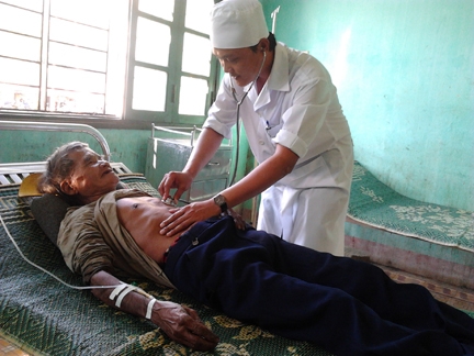 Y sĩ Võ Văn Thạch thăm khám cho bệnh nhân Hồ Văn Nhu (80 tuổi) ở thôn Trà Kim, xã Trà Xinh.  