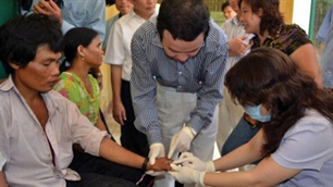 Bộ trưởng Bộ Y tế Nguyễn Thị Kim Tiến (bên phải) kiểm tra bệnh nhân mắc bệnh lạ (Ảnh: TNO).