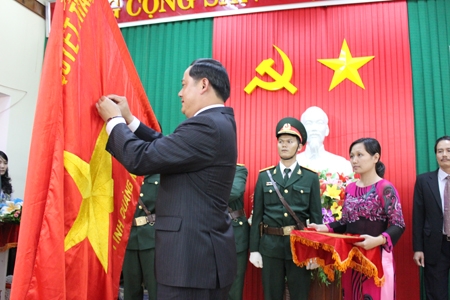 Đồng chí Xây-Xôn Xi-Phăn-Đon - Bí thư, Tỉnh trưởng tỉnh Champasak gắn Huân chương Tự do Itsara hạng III lên lá cờ đỏ sao vàng