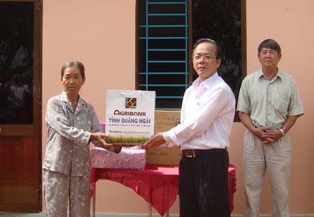Ông Nguyễn Văn Hồng - Phó Giám đốc Ngân hàng Nông nghiệp và Phát triển nông thôn chi nhánh Quảng Ngãi trao quà cho bà Nguyễn Thị Tuyến tại lễ khánh thành nhà.