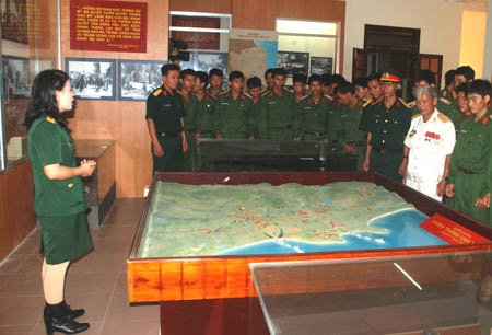Cán bộ Phòng Chính trị (bên trái) giới thiệu truyền thống của LLVT tỉnh cho các chiến sĩ tại Nhà truyền thống LLVT tỉnh.