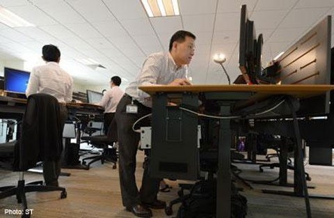 Đứng khi làm việc sẽ giúp dân văn phòng chống được các triệu chứng của “bệnh ngồi” như đau vùng cổ, vai gáy và lưng. Ảnh: Strait Times