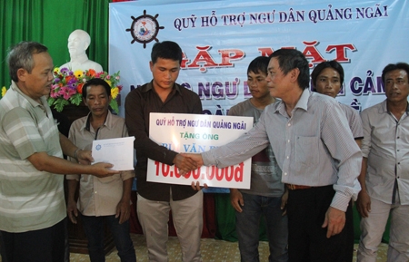 Ông Nguyễn Xuân Huế (bên phải) trao quà, tiền hỗ trợ cho ngư dân.