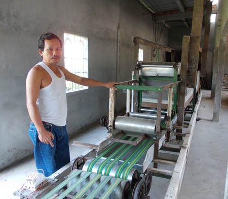Lão nông Nguyễn Đăng Khiêm bên chiếc máy sản xuất bánh tráng  hoàn toàn tự động từ khâu làm bánh đến khâu phơi bánh.