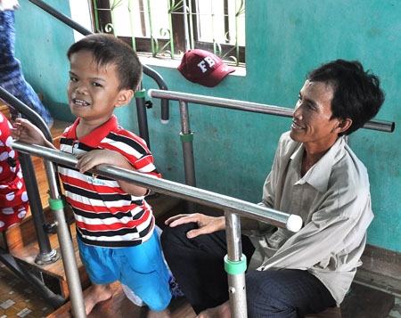 Cậu bé “tí hon”  Phan Nguyễn Thành Đạt cùng cha trong phòng tập chức năng.