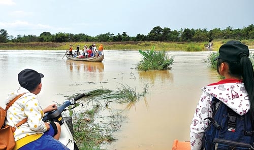 Con đò chở người dân “ốc đảo” An Phú vượt qua đoạn đường bị nước ngập chia cắt (Ảnh chụp ngày 23/7/2013). Ảnh: TỬ TRỰC