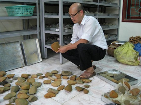 Chuyên gia Viện Khảo cổ học Việt Nam xem các di vật công cụ lao động bằng đá vừa được khai quật tại di chỉ Sủa Cá. Ảnh: Tin tức