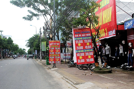 Các cửa hiệu buôn bán giăng biển quảng cáo trên vỉa hè tuyến phố Quang Trung.