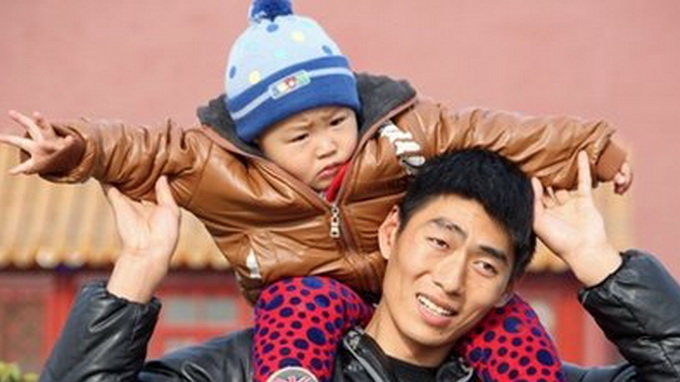 Một em bé Trung Quốc là con một được cha đưa đi dạo ở Bắc Kinh - Ảnh: AFP