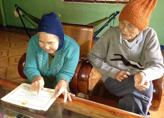 Bà Vương rơm rớm nước mắt khi cầm trên tay tấm Bằng khen Gia đình kháng chiến được ký từ năm 1975.