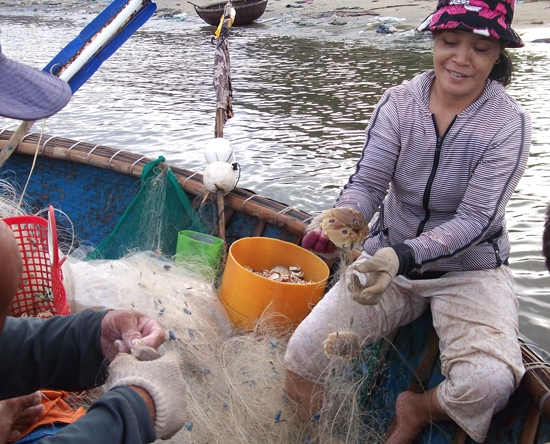 Chị Trần Thị Nhơn ở Sơn Trà phấn khởi phụ giúp chồng gỡ ghẹ sau chuyến ra khơi.