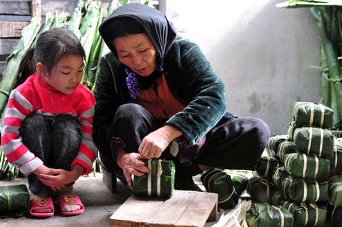 Bà và cháu gói bánh chưng ngày tết.