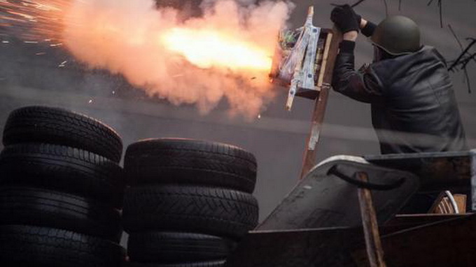 Một người biểu tình bắn súng tự tạo về phía lực lượng chính phủ Ukraine  - Ảnh: Reuters