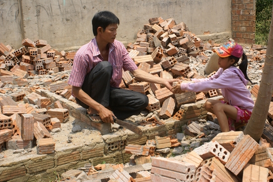 Cha con anh Nguyễn Trinh, thôn Gò Da, xã Sơn Linh (Sơn Hà) cố tìm kiếm những viên gạch lành trong đống đổ nát sau lốc xoáy.                               Ảnh: T.NHỊ