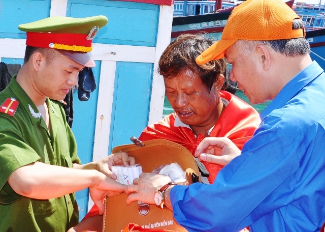 Đại diện đoàn công tác trao cờ và tặng tủ thuốc cho ngư dân