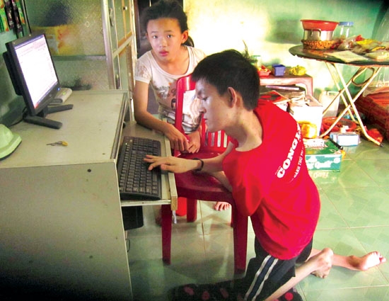 Cậu bé Ngô Đức Quang và em gái đang học tiếng Anh trên máy tính.