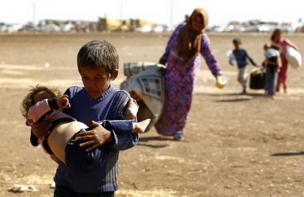Một cậu bé tị nạn người Kurd ở Syria ẵm em sau khi vượt qua biên giới Syria-Thổ Nhĩ Kỳ hôm 23-9-2014. Gia đình cậu phải chạy sang Thổ Nhĩ Kỳ để tránh bạo lực do nhóm cực đoan Nhà nước Hồi giáo tự xưng gây ra - Ảnh: Reuters