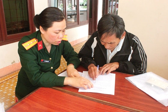 Trung úy Vũ Thị Hồng Thúy đang hướng dẫn người dân làm thủ tục hồ sơ theo Quyết định 62 của Thủ tướng Chính phủ.