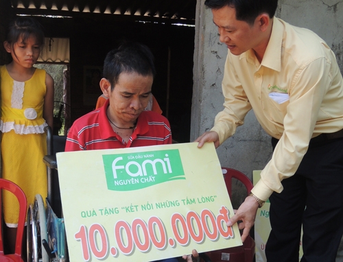 Đại diện Vinasoy trao tiền hỗ trợ cho người nghèo, tàn tật.