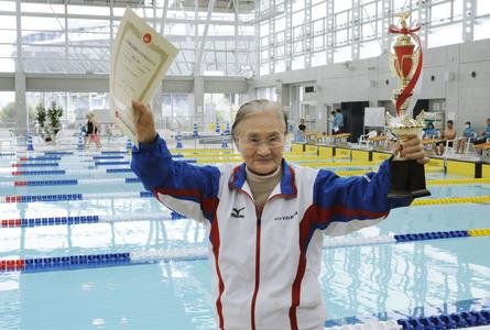  Cụ bà Nagaoka giơ cao phần thưởng ghi nhận thành tích bơi lội mới nhất - Ảnh: CCTV