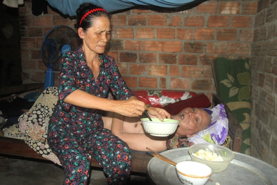 Bà Mai khó khăn bón từng muỗng cơm cho chồng.