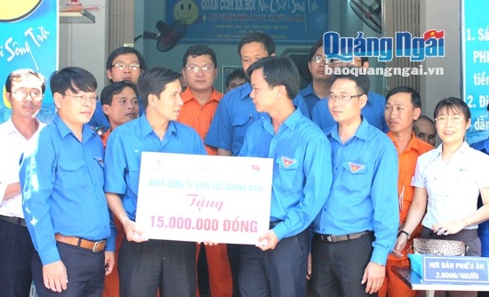 Anh Lê Việt Hùng (cầm bảng bên phải) trao tiền hỗ trợ của Đoàn Thanh niên Công ty Điện lực Quảng Ngãi cho Quán cơm xã hội “Nụ cười Sông Trà”.