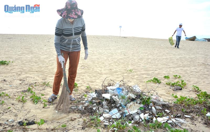 Các chị em phụ nữ kinh doanh tại bãi biển thôn Tân An (Nghĩa An) dọn rác trên bãi biển.