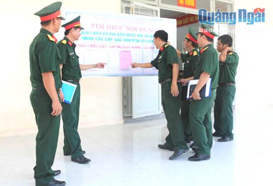 Cán bộ, nhân viên Ban CHQS huyện Minh Long tìm hiểu các văn bản, quy định mới được niêm yết tại đơn vị.