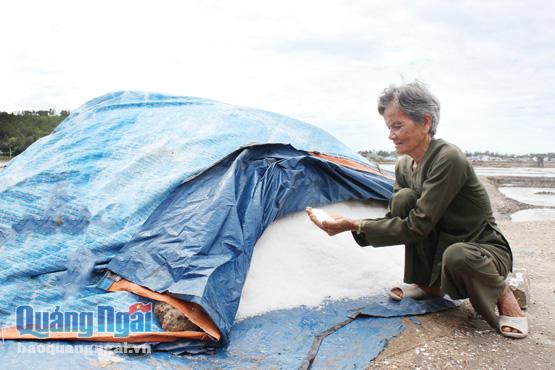 Bà Nguyễn Thị Cho bên số muối thu hoạch trong năm nay, phải chất đống vì giá muối hạ thấp.