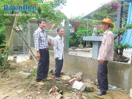 Ông Dương Minh Tòng (bên trái) đang trò chuyện với người dân trong thôn về việc làm đường giao thông nông thôn.