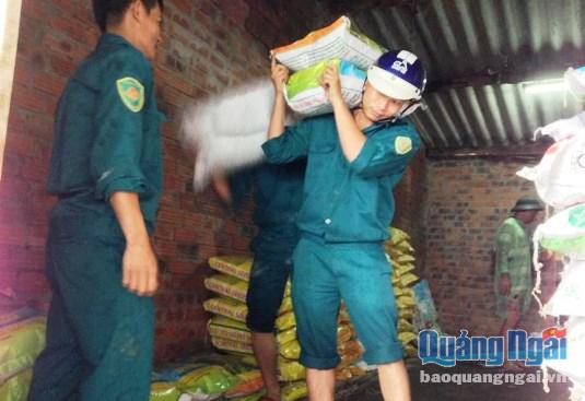 Lực lượng dân quân hỗ trợ người dân di chuyển lúa gạo đến nơi cao ráo