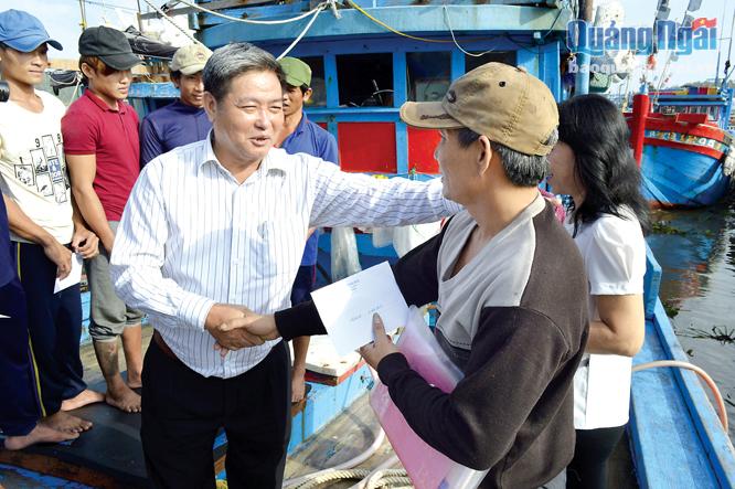 Chủ tịch LĐLĐ tỉnh Trần Văn Thanh trao tiền hỗ trợ, động viên thuyền trưởng Võ Lai cùng 10 ngư dân may mắn thoát nạn trở về từ vùng biển đảo Hoàng Sa. Ảnh: PV