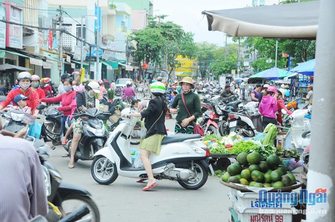 Người bán hàng rong, rau xanh, quần áo tràn xuống đường buôn bán khiến cho giao thông tại nút giao thông Nguyễn Nghiêm - Nguyễn Bá Loan trở nên lộn xộn.