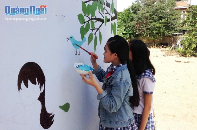 Các em học sinh tham gia tô màu cho bức bích họa nhà vệ sinh trường học