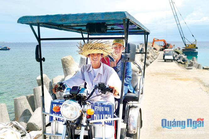 Bị liệt cả hai chân, nhưng ngư dân Bùi Huệ vẫn nhạy bén tham gia làm dịch vụ lái xe điện phục vụ du khách đến đảo Bé.  ảnh: ý thu