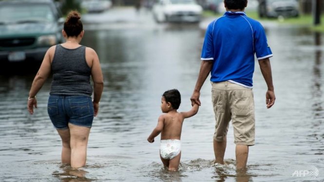 Người dân lội xuyên qua vùng nước lụt tại Galveston - Ảnh: AFP