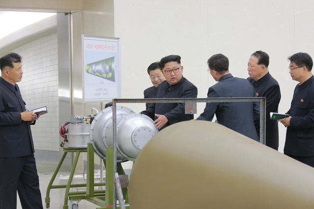 Nhà lãnh đạo Triều Tiên Kim Jong Un (thứ ba từ trái sang) chỉ đạo các nhà khoa học Triều Tiên khi đứng cạnh một thiết bị được cho là vũ khí hạt nhân mới - Ảnh: REUTERS