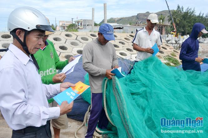 Chủ tịch nghiệp đoàn nghề cá An Hải Nguyễn Quốc Chinh (bên trái) phát tài liệu tuyên truyền cho ngư dân.