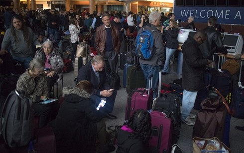  Hành khách chờ đợi trong sân bay tối om vì mất điện. Ảnh : Reuters