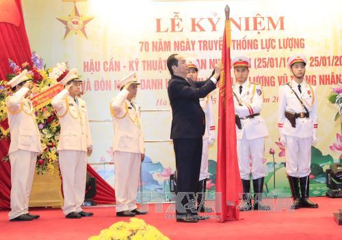 Chủ tịch nước Trần Đại Quang gắn huy hiệu Anh hùng Lực lượng vũ trang nhân dân lên lá cờ truyền thống của lực lượng Hậu cần - Kỹ thuật Công an nhân dân. Ảnh: TTXVN