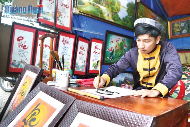 Ông đồ trẻ Nguyễn Việt Hiệp đang cho chữ ở chợ hoa xuân.