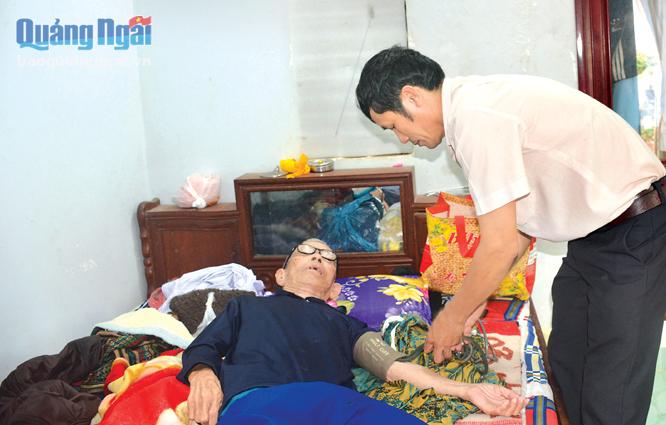 Anh Nguyễn Công Cảnh kiểm tra huyết áp cho cụ Nguyễn Văn Huy ở xã Bình Trị già yếu không đi lại được.